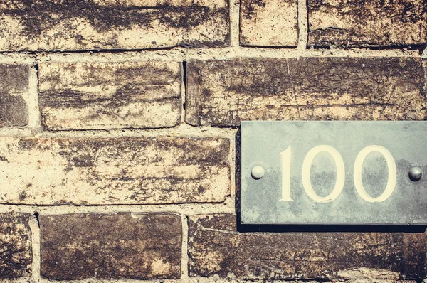 Número de casa acurrucado en una pared de ladrillo . —  Fotos de Stock