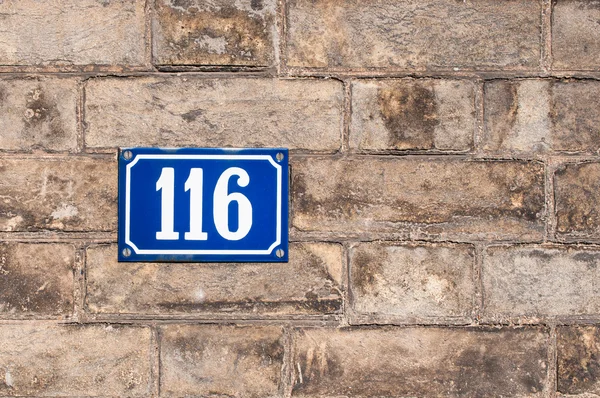 Nomor seratus enam belas dicat di pelat logam di batu bata w — Stok Foto