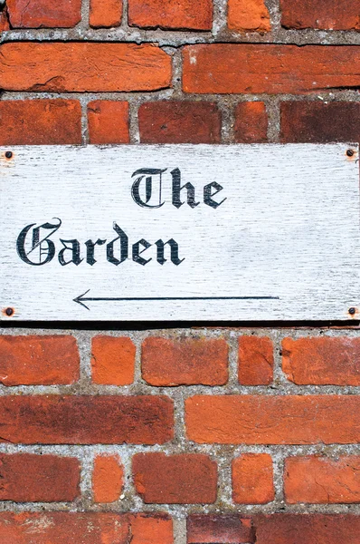 Sign for 'The Garden' on a brick wall background — Stock Photo, Image