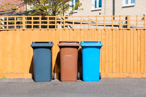 Drie plastic afvalbakken buiten een huis Stockafbeelding