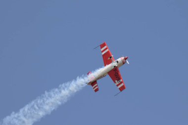 Kırmızı akrobatik monoplane EA300 Mavi gökyüzünde beyaz duman