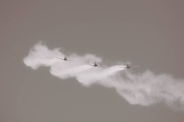Duman ve gri gökyüzü ile akrobatik gösterimde üç uçak, siyah ve beyaz fotoğraf
