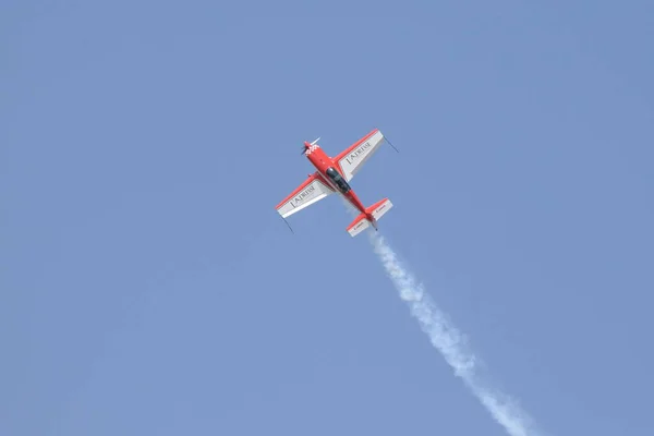Kırmızı akrobatik monoplane EA300 Mavi gökyüzünde beyaz duman