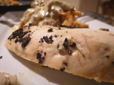 Kızarmış tavuk filetosu, mantar, patates kızartması ve sos beyaz tabakta.