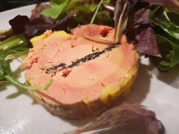 Mantarlı kaz ciğeri ve beyaz tabakta salata.