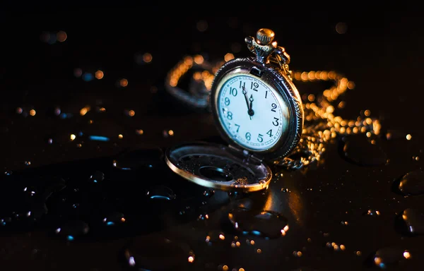 Siyah bir arka plan damla ile bir cep saati