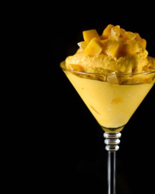Siyah zemin üzerinde mango aromalı sarı renkli dondurmaya yakın plan..