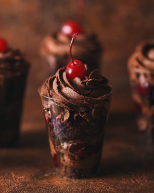 Kahverengi arka planda bir şenlik partisi için bardakta çikolatalı tatlı ve kirazlı kokteyl. gurme ikramlar ve tatlılar