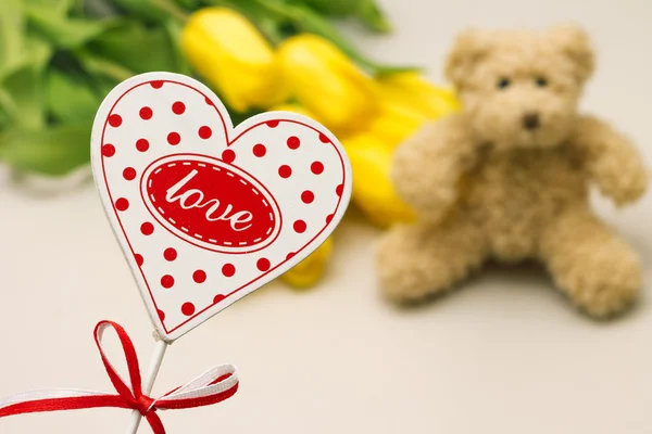 Hart met het woord Love. Speelgoed en bloemen op achtergrond — Stockfoto