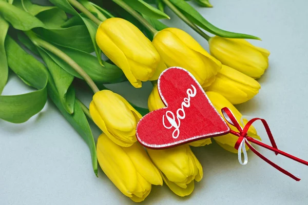 Yellow tulips and plate in shape of heart — Stock Photo, Image