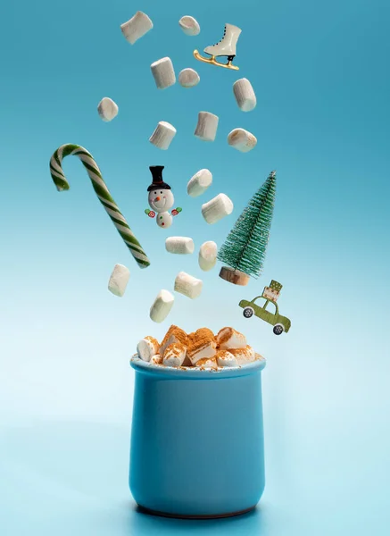 Świąteczna kartka koncepcyjna ze słodkim napojem i latającymi symbolami świąt Bożego Narodzenia: cukierkami, choinką, bałwanem i piankami.. — Zdjęcie stockowe