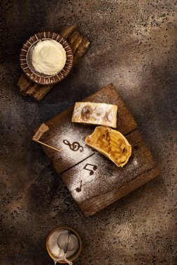 Kahverengi zemin üzerinde elma, dondurma ve şeker tozu bulunan klasik Avusturya turtası..