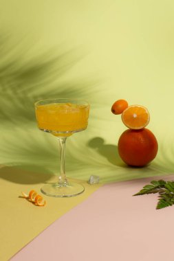 Yaz suyunu buzla, taze portakalla, limonla ve kumkatla tazeleyen yeşil arka planda sert arka planda palmiye yaprakları. Turunçgil meyvelerini dengelemek ve ferahlatıcı bir kokteyl..