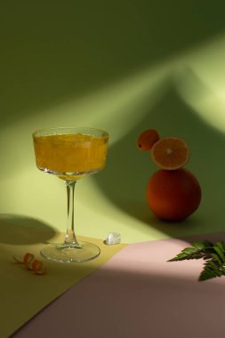 Yaz suyunu buzla, taze portakalla, limonla ve kumkatla yeşil arka planda sert gölgelerle tazelemek. Turunçgil meyvelerini dengelemek ve ferahlatıcı bir kokteyl..