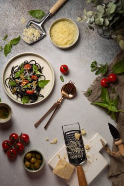 Kurutulmuş domatesli siyah spagetti, parmesan peyniri, pesto, fesleğen, taze marjoram ve İtalyan pastası için farklı yemekler..