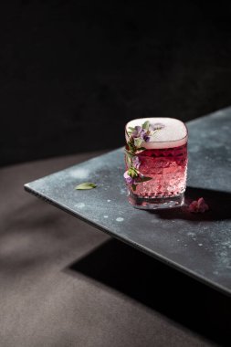 Cin, soda, tonik su, gül şampanyası ve buz küpleri, mor çiçeklerle süslenmiş, mavi arka planda adaçayı yaprakları. Bir parti için şık bir kokteyl..