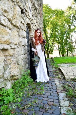 Taş bir kalenin, metal bir kapının ve hapishane penceresinin önündeki kaldırım taşlarının üzerindeki seksi, uzun saçlı genç kız.