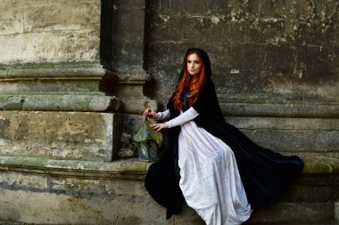 Taş bir kalenin, metal bir kapının ve hapishane penceresinin önündeki kaldırım taşlarının üzerindeki seksi, uzun saçlı genç kız.