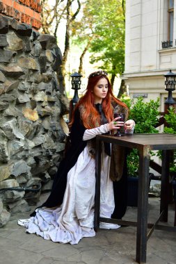 Seksi, uzun saçlı, şatonun terasında oturan genç kız.