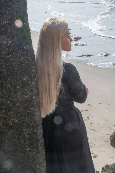 ドレスで北海のビーチの石の上に美しい足を持つブロンド — ストック写真