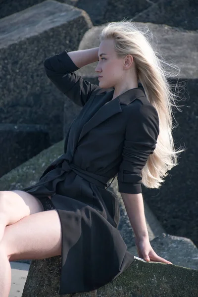 ドレスで北海のビーチの石の上に美しい足を持つブロンド — ストック写真