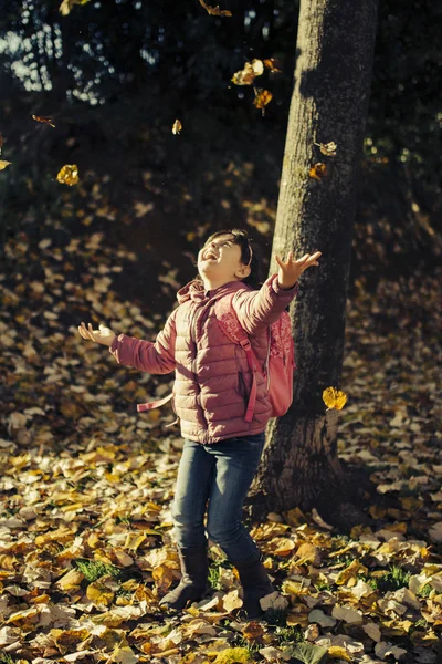 Bambina che gioca in foglie cadute — Foto Stock
