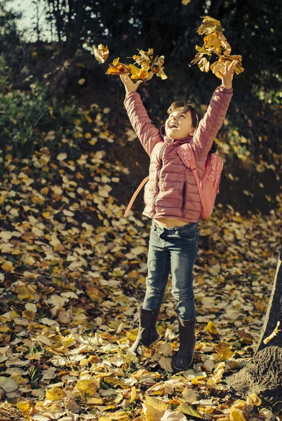 Bambina che gioca in foglie cadute — Foto Stock