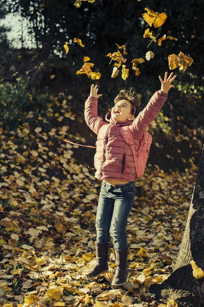 Bambina che gioca in foglie cadute — Foto Stock