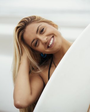 Kız sahilde sörf tahtası tutar