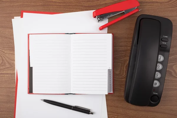 Açık not defteri ve ahşap doku üzerinde siyah telefon.