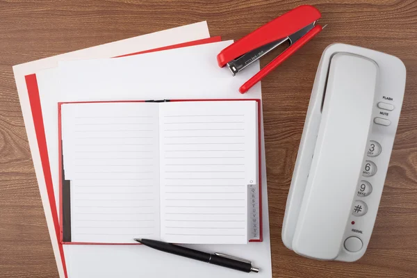 Açık not defteri ve ahşap doku üzerinde beyaz telefon.