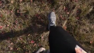 Sonbahar ormanında yürüyen bir kadının yavaş çekim görüntüsü. Düşen yapraklar yeri kaplıyor, rahat, sakin ve atmosferik bir düşüş havası yaratıyor..