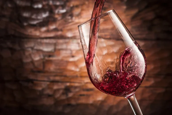 Vino rosso versando su fondo legno — Foto Stock