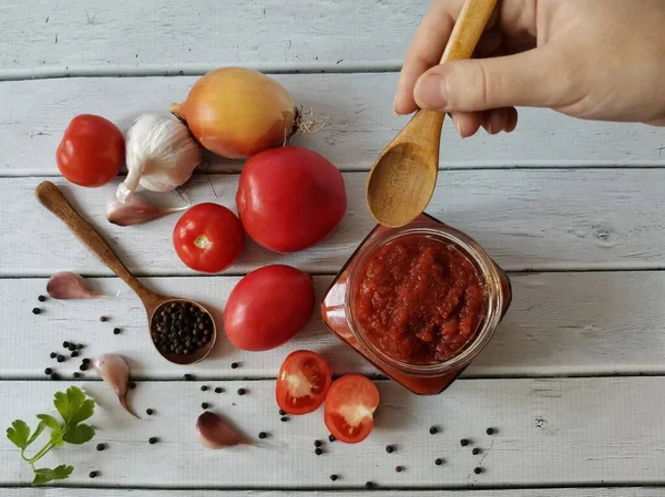 Ev yapımı lezzetli ketçaptan örnek alın. El, kaşık ve ketçap çerçevede.