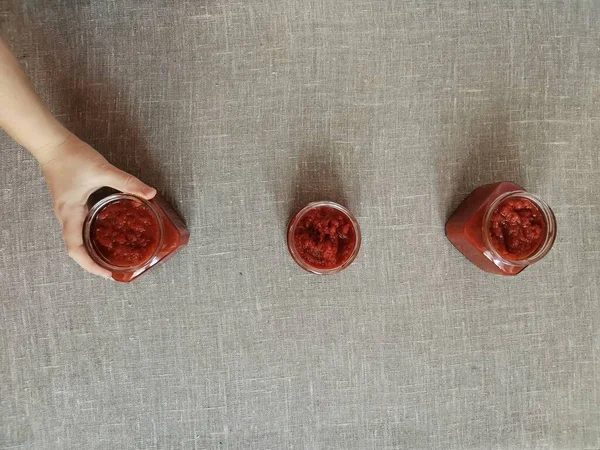 Mão das mulheres leva uma das três latas de ketchup — Fotografia de Stock