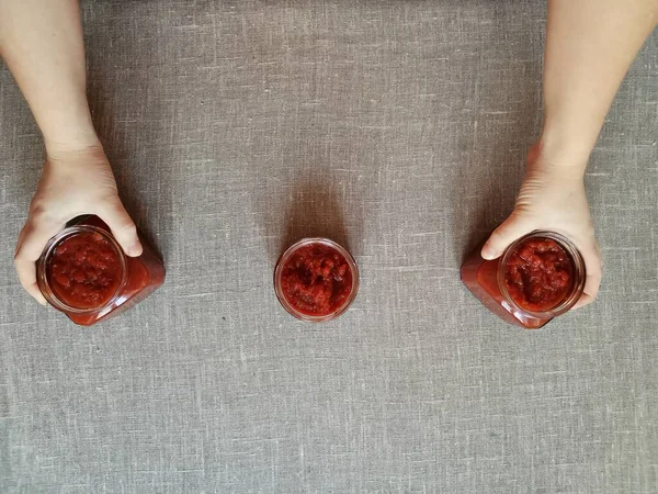 Mão das mulheres leva duas de três latas de ketchup — Fotografia de Stock