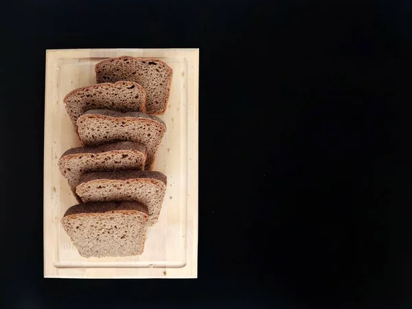 Çavdar ekmeği dilimleri siyah arka planda tahta bir tahta üzerinde 
