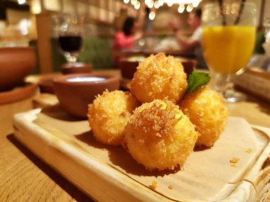 Restoranın bulanık arka planında ahşap tepside peynir topları.