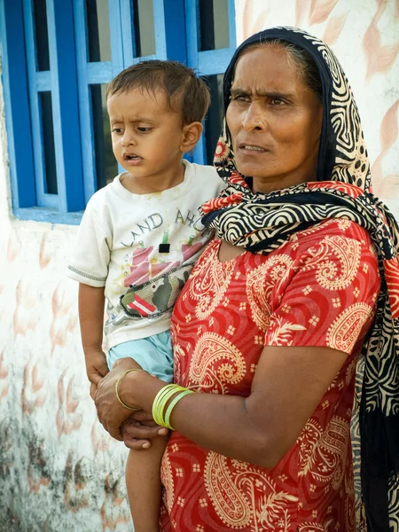 Amroha, Uttar Pradesh, Hindistan - 2011 :Elinde çocuk lu ve kırmızı sari ile Kırsal Hintli kadın