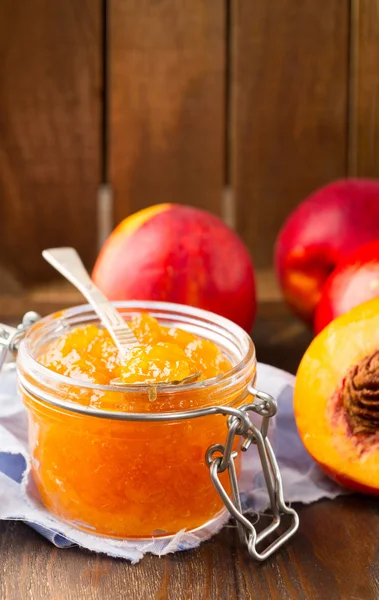 Банка персикового варенья со свежими фруктами — стоковое фото