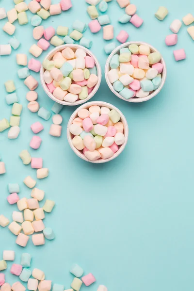 Kleine gekleurde marshmallows op blauwe tafel — Stockfoto