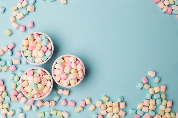Kleine gekleurde marshmallows op blauwe tafel — Stockfoto