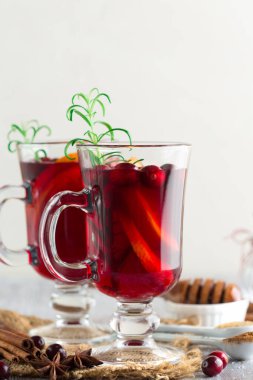 Sıcak Noel şarabı, portakal dilimleri, kızılcık, anason ve tarçınlı bardaklarda beyaz kırsal ahşap arka planda. Kış tatili konsepti, kopyalama alanı.