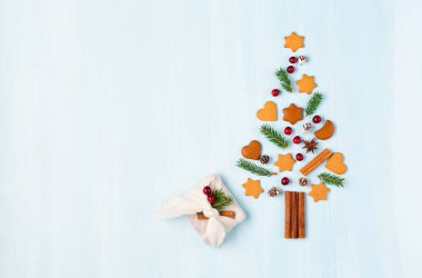 Xmas zencefilli kurabiyelerden, tarçınlı, kızılcıklı ve mavi arka planda el yapımı furoshiki hediyesinden yapılmış Noel ağacı. Sıfır Noel ve yeni yıl kış konsepti. Düz konum, boşluk kopyala, üst görünüm