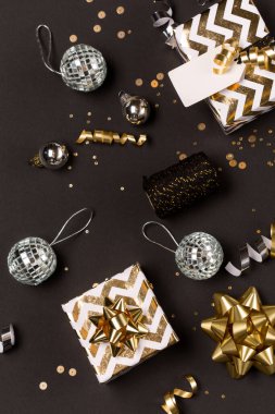 Noel kompozisyonu. Altın ve gümüş madalyalar, ayna disko topları, koyu siyah arka planda hediyeler. Noel, kış, yeni yıl konsepti. Düz konum, üst görünüm, kopyalama alanı.