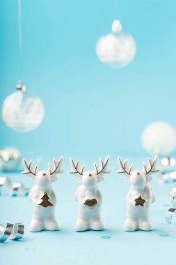 Küçük camlı beyaz ren geyikli Noel kartı, gümüş süslemeler, açık mavi arka planda ayna disko topları. Kış festivali konsepti, kopyalama alanı.