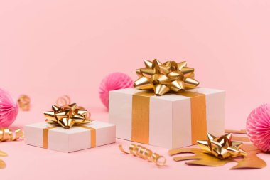 Bayram tebrik kartı şablonu. Altın tropik yapraklar Monstera, şenlikli hediye kutusu, pembe arkaplanda altın ve pembe süslemeler. Noel, yeni yıl, doğum günü konsepti, fotokopi alanı.