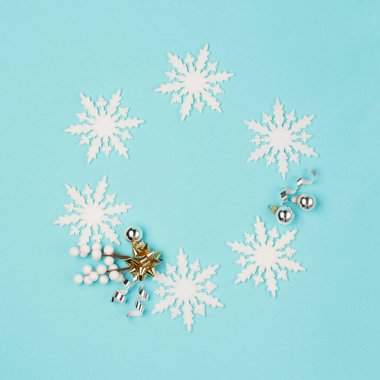 Noel ya da kış kompozisyonu. Kar tanelerinden yapılmış çerçeve, pastel mavi arka planda altın ve gümüş süslemeler. Noel, kış, yeni yıl konsepti. Düz konum, üst görünüm, kopyalama alanı.