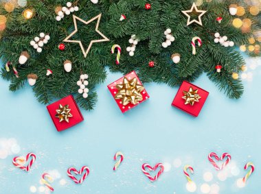 Noel tatili yeni yıl kutlaması kartı. Xmas kırmızı hediye kutuları, baston şekerler, gümüş beyaz süslemeler, mavi Noel ağacı dallarında meşe palamutları. Düz konum, üst görünüm, kopyalama alanı.