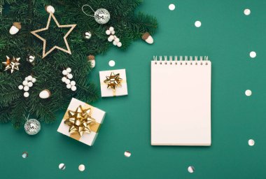 Noel tatili yeni yıl kutlaması kartı. Xmas altın hediye kutuları, boş defter, gümüş beyazı süslemeler, yeşil Noel ağacı dallarında meşe palamudu. Düz konum, üst görünüm, kopyalama alanı.